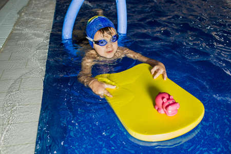 child dressed in clothes for swimming trained to swim in the pool