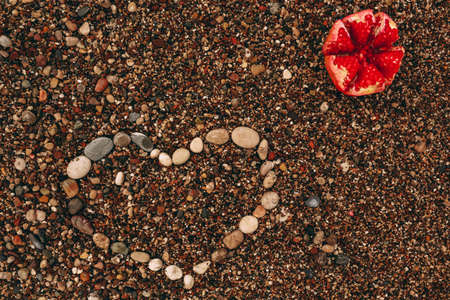 pomegranate and heart shape from stones, fruit on the beach close-upの写真素材