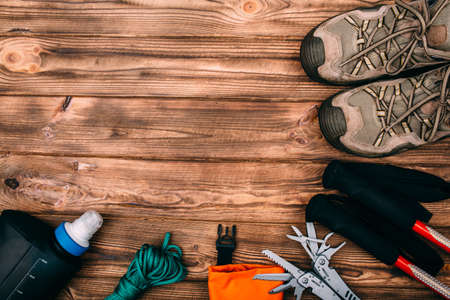 Top view of equipment for hiking and travel on wooden table with empty space in the middle. Items...