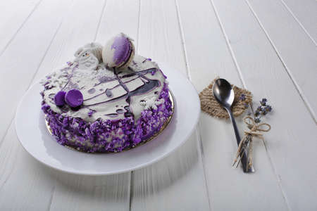 creamy cake with blueberry jam and macaroon on white wooden table background. Top view