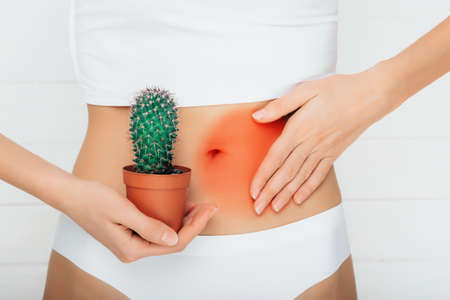 woman dressed in underwear, suffering from stomach ache , gastritis or menstruation, stomach trouble close- upの写真素材