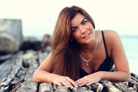 beautiful tanned smiling woman relaxing on the sea pier in lingerie