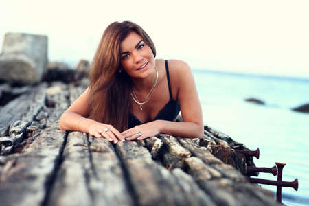 beautiful tanned smiling woman relaxing on the sea pier in lingerie