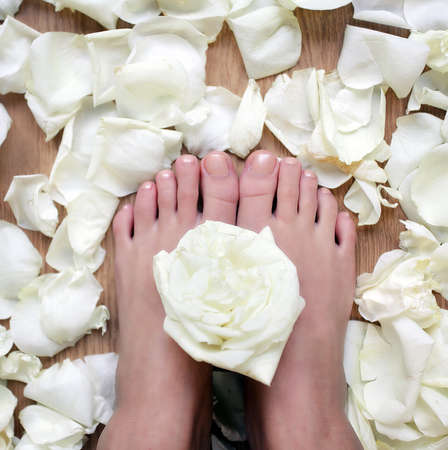 beautiful women feet with rose flower and petals in spa