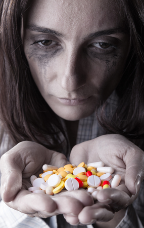Pills in women's hands on dark background. Focus on pillsの写真素材