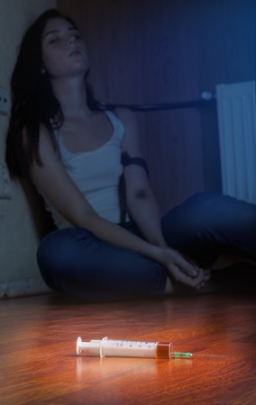 Close-up on the floor of the syringe with the drug. In the background, a young drug addictの写真素材