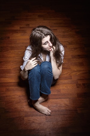 Sad woman sitting alone in a empty roomの写真素材