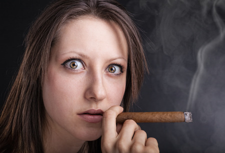 Portrait woman with cigar on a dark backgroundの写真素材