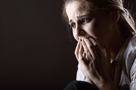 Young crying woman on dark backgroundの写真素材