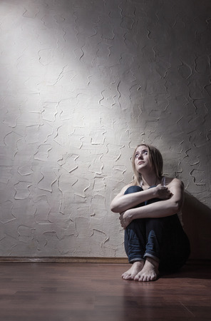 Young sad woman sitting alone on the floor in an empty roomの写真素材