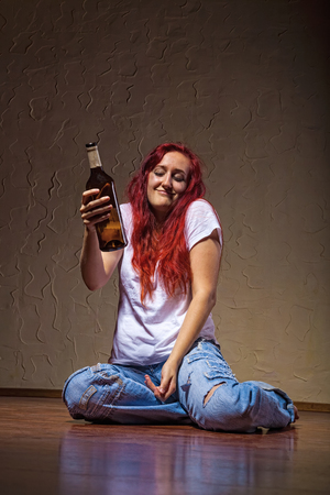 A young woman from a bottle of wine-drinking at home sitting on the floorの写真素材