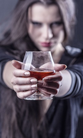 Young woman in depression, drinking alcohol. Focus on glassの写真素材