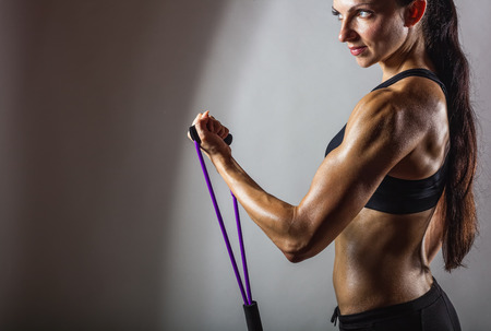 Sportswoman exercising with a resistance band on grey  backgroundの写真素材