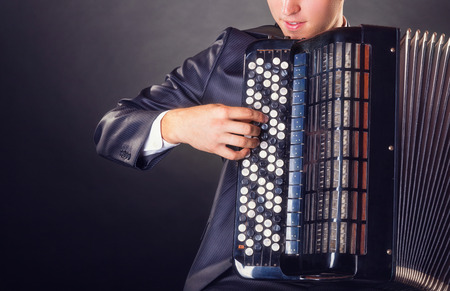 Musician playing the accordion against a black backgroundの写真素材