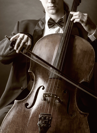 Cellist playing classical music on cello on black background
