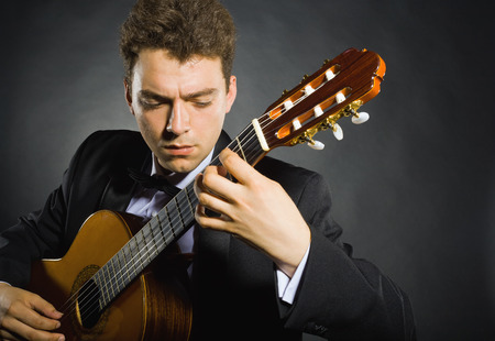 Guitarist. Man playing guitar on black backgroundの写真素材
