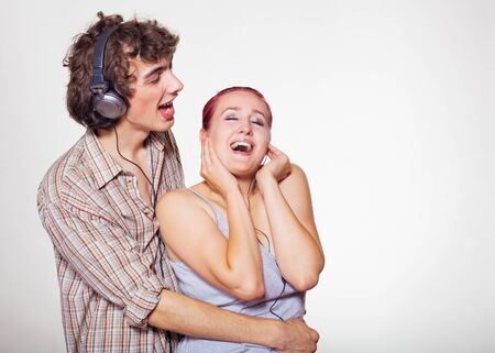 A young guy and girl listening to music through headphones on a white backgroundの写真素材