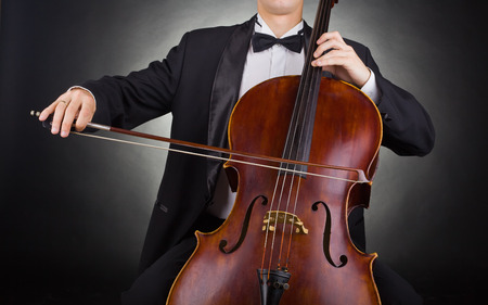 Cellist playing classical music on cello on black backgroundの写真素材