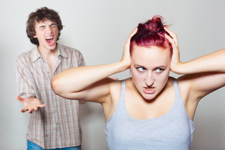 Furious, the husband yells at his wife, unhappy woman covered her ears with his handsの写真素材