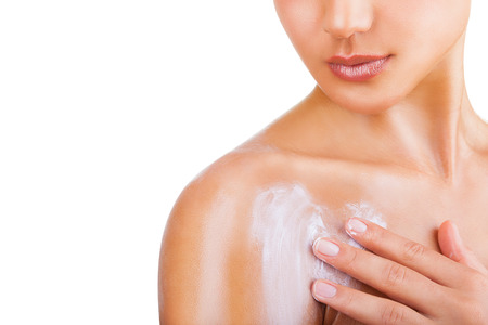 Close-up of a woman cares about her shoulder applying cosmetic cream. Isolated on white backgroundの写真素材