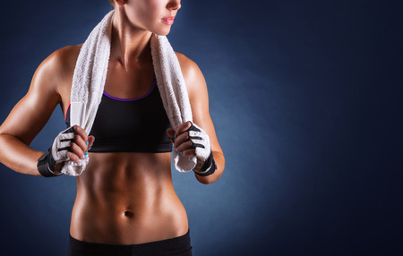 Young sports woman after workout with towel on his shoulders on a dark background Young sports woman after workout with towel on his shoulders on a dark background