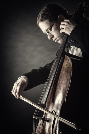 Cellist playing classical music on cello on black backgroundの写真素材