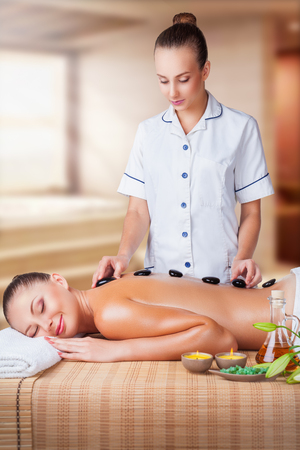 Stone-therapy. Beautiful young woman with closed eyes get a relaxing massageの写真素材