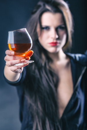 Young woman in depression, drinking alcohol. Focus on glass