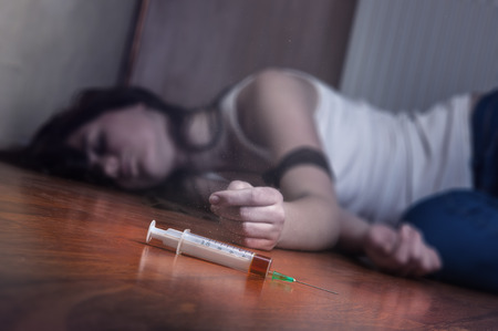 Close-up on the floor of the syringe with the drug. In the background, a young drug addict