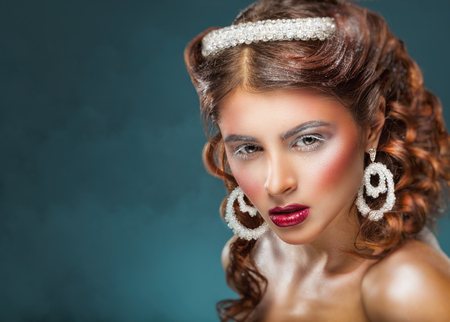 Beautiful young woman with wavy hair and fashion make-up and jewelryの写真素材