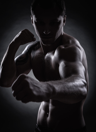 Fighter silhouette. Handsome athletic man in boxing stand on a dark backgroundの写真素材