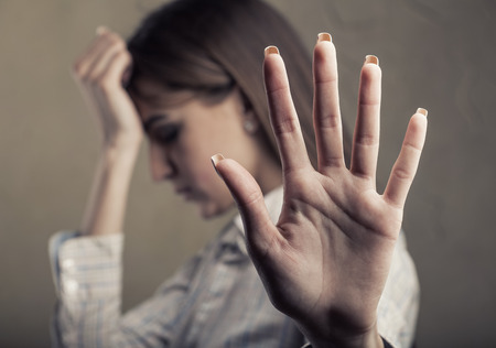 Young tired woman shows a hand sign stop. Focus on the handの写真素材