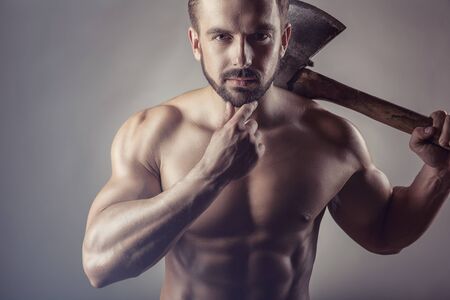 Handsome muscular man with naked bare torso on grey background with village axの写真素材