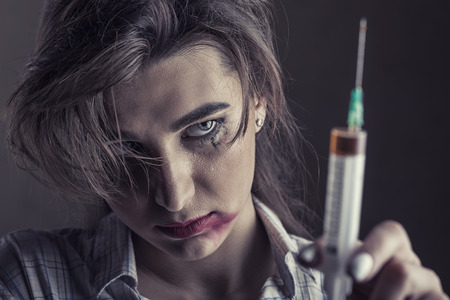 Young woman with drug addiction on dark background.  Focus on girl's faceの写真素材