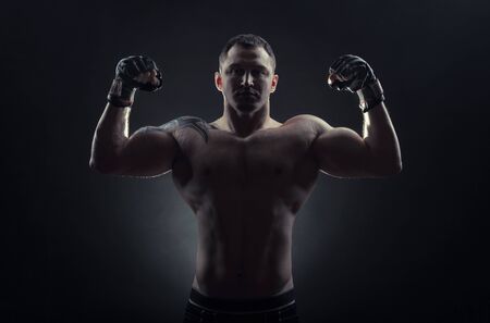 Boxing man ready to fight. Boxer with strong hands in gloves before a fight on a black backgroundの写真素材