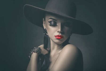 Fashion beautiful woman with red lips and hat on a dark background. Vintage