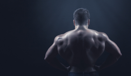Strong athletic man back on dark backgroundの写真素材