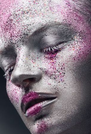Fashion makeup. Close-up of a young woman with silver makeup with pink sequinsの写真素材
