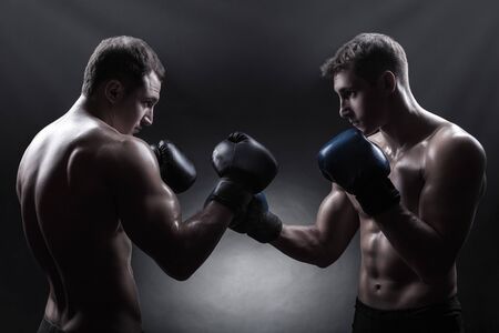 Two boxer with boxing gloves before a fight against a dark backgroundの写真素材