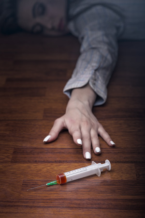 Close-up on the floor of the syringe with the drug. In the background, a young drug addictの写真素材