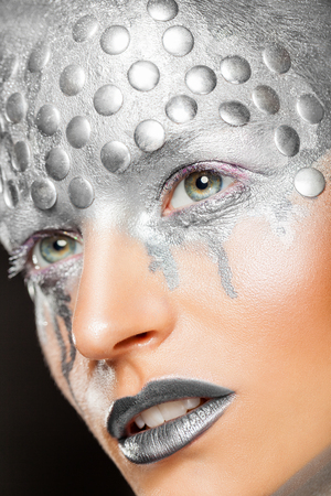 Art fantasy makeup. Close-up of young woman with fashion silver makeup with rivetsの写真素材