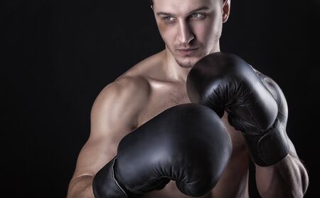 Young boxer in boxing gloves against a black background. Boxing conceptの写真素材