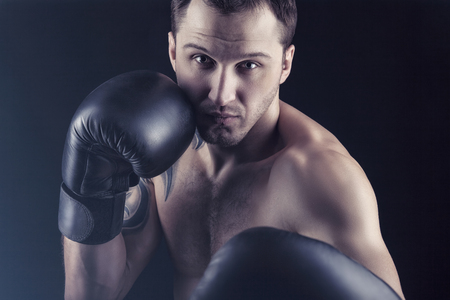 Boxing concept. Boxer with an aggressive look in boxing gloves before a fight on a black backgroundの写真素材