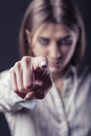 An angry young woman is pointing a finger at the camera. Focus on the fingerの写真素材