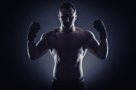 Boxing man ready to fight. Boxer with strong hands in gloves before a fight against a black backgroundの写真素材