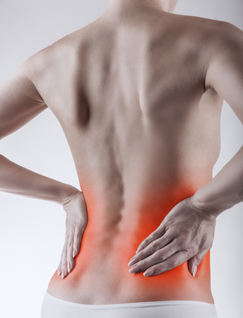 Close-up of a woman's back with pain against a light backgroundの写真素材