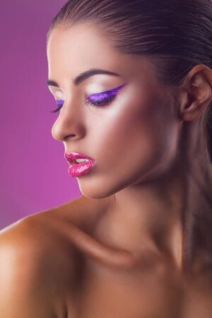 Close-up of young woman with fashion makeup on a purple backgroundの写真素材