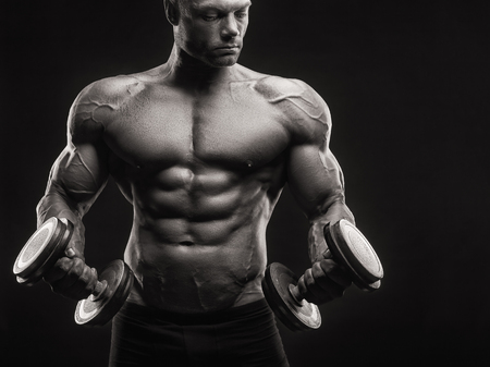 Bodybuilder. Fit muscular bodybuilder man exercising with dumbbell. Black and white imageの写真素材