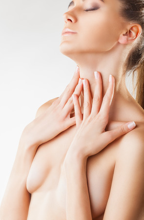 Beautiful young woman with clean skin covering her nude breast isolated on a white backgroundの写真素材