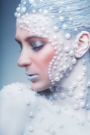Fantasy make-up. Portrait of beautiful woman with fantasy make-up with white pearls on a grey backgroundの写真素材